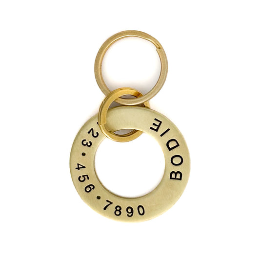 Brass washer style dog name tag engraved with name and phone number.
