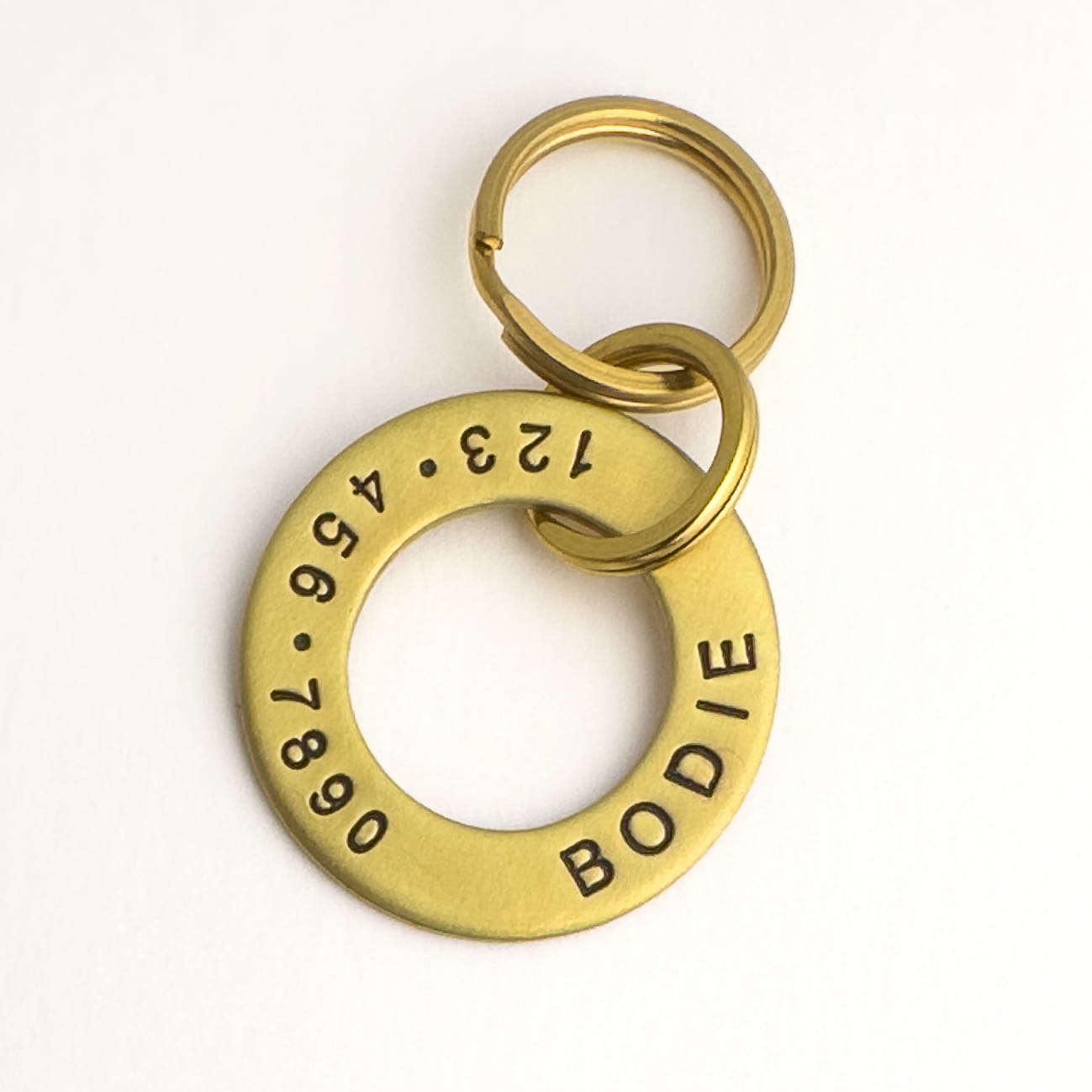 Solid brass washer personalized with dog name and owners phone number. Two split rings to connect the tag to dog's collar.