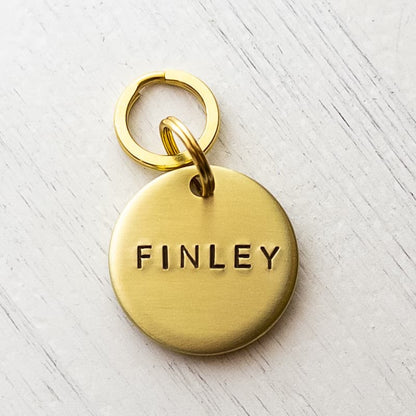 Round solid brass dog tag with split rings.