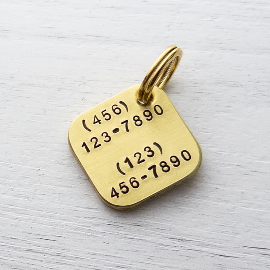 Two phone numbers on the back of a dog tag. 